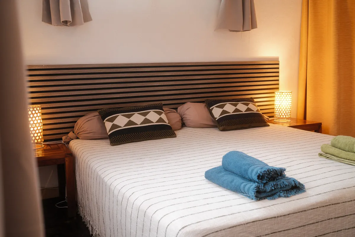 Chambre chaleureuse avec tête de lit en tasseaux, lampes en rotin et coussins graphiques