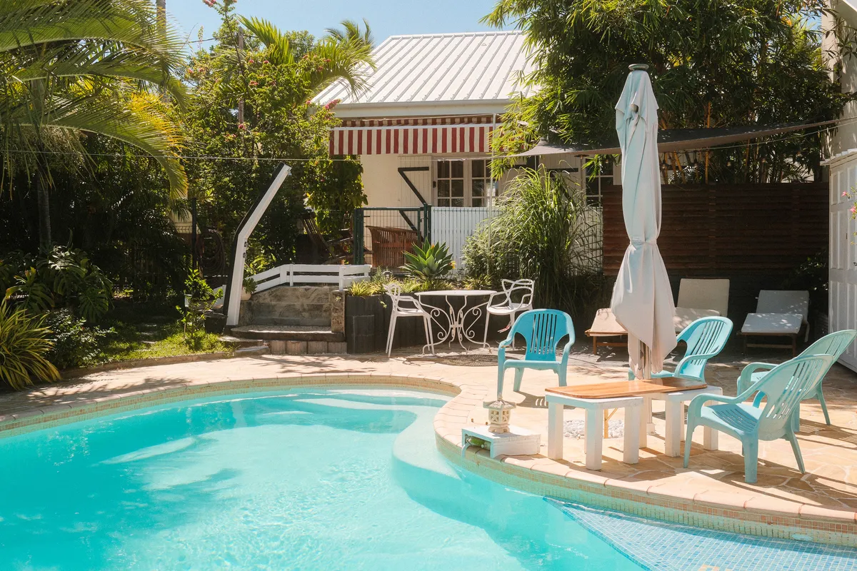 Piscine de la Villa Boucan entourée de palmiers avec chaises et terrasse en arrière-plan